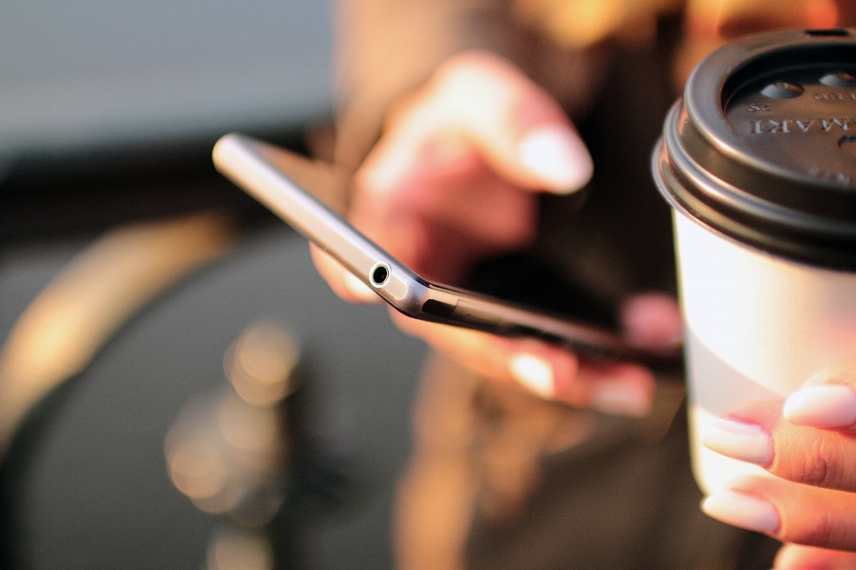 Smartphone escribiendo mano café