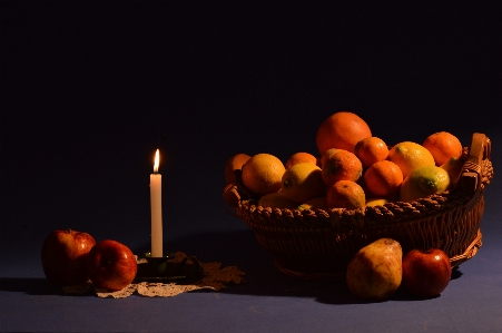 Candle oranges apples basket Photo